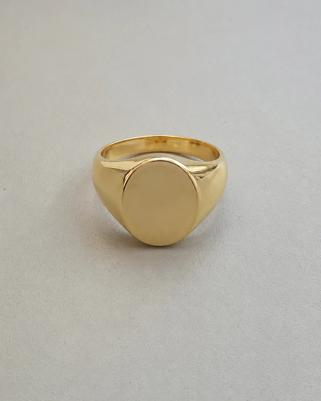 A plain smartphone photo of a gold signet ring on a desk